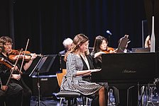 Mädchen am Flügel mit Orchester